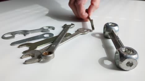 woman choosing tool from multiple spanner tools on worktop, close up