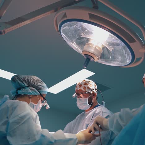 plastic surgery. group of doctors in protective uniform performing a surgery on a patient in modern clinic. view from below.