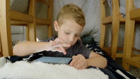 front view of cute caucasian boy using digital tablet in a comfortable home 4k