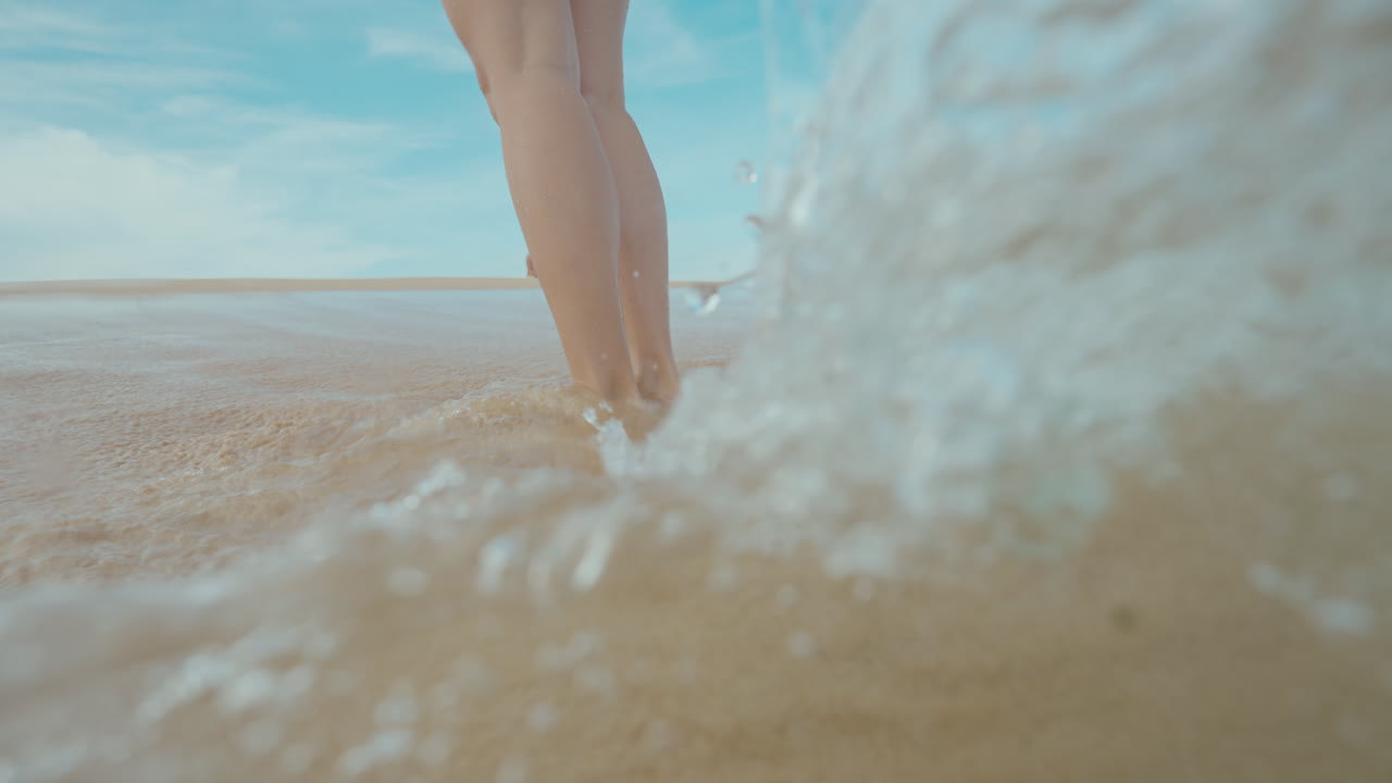 Person walking in shallow water on the beach