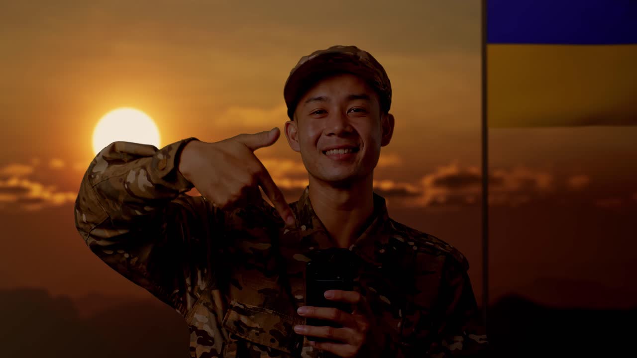 해가 지는 동안 스마트폰을 가진 군인