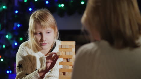 mamá e hija juegan un juego de mesa con bloques de madera