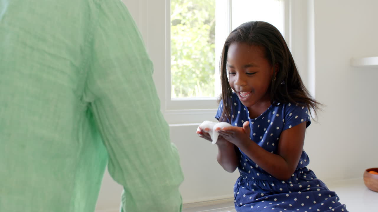 African American, Young girl playfully imitating adult with tissue at home, expressing surprise