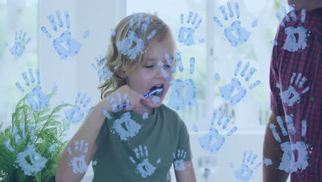 video of handprints over caucasian boy brushing teeth