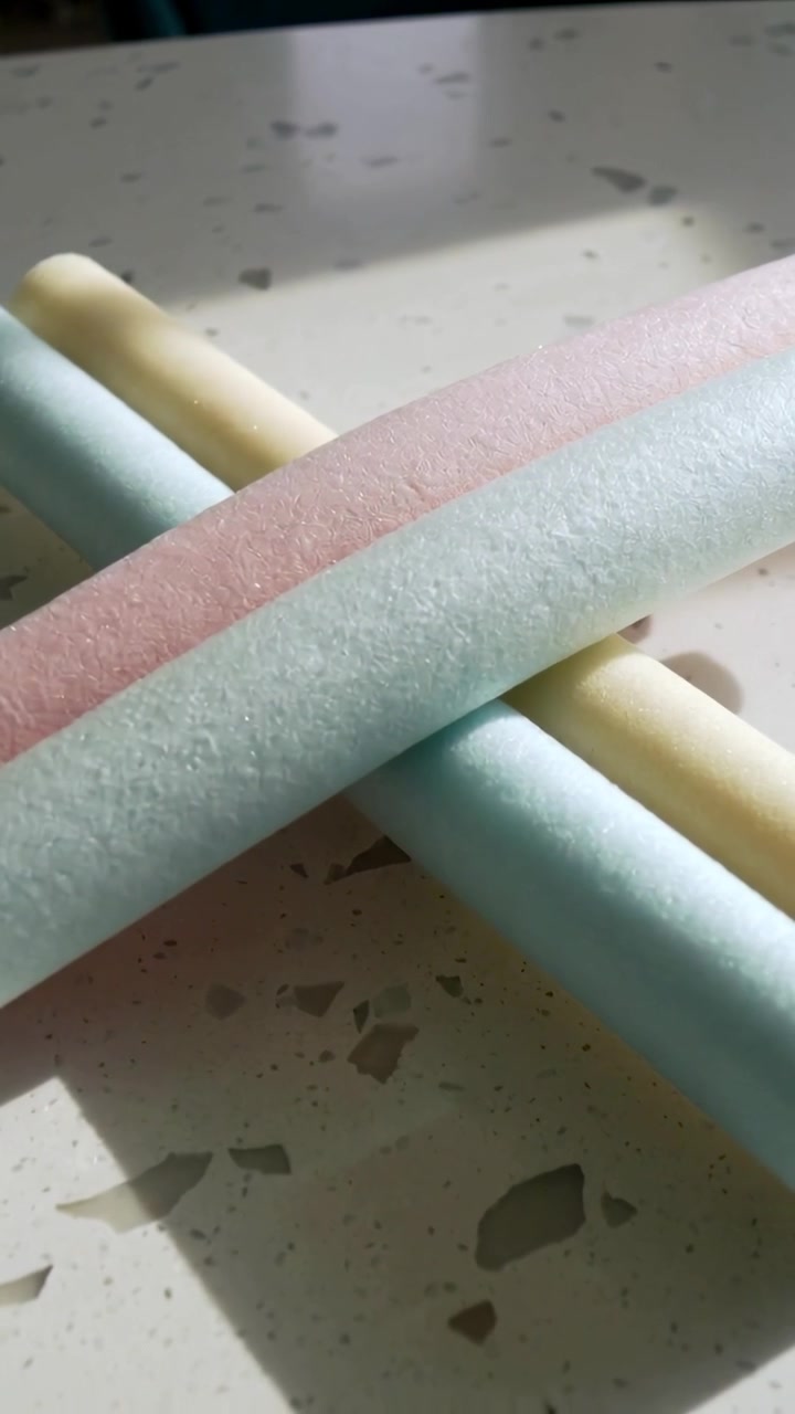 Vertical video: Tilting camera revealing three pastel foam rods on speckled counter to show layout