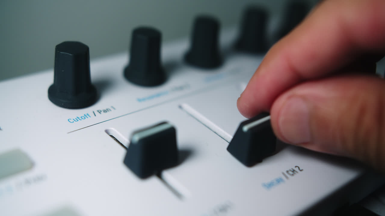 Beautiful slow motion and close up shot. A latin musician producer moves the fade of a midi controlled keyboard in his home studio.