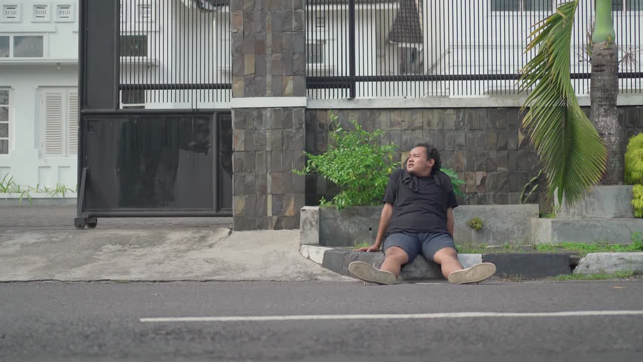 Man Sitting on the Sidewalk