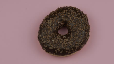 sweet donut rotating on pink background. top view. tasty, fresh sprinkled donut