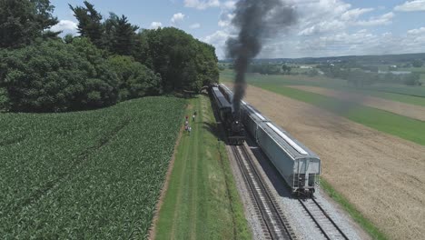 vista aérea de las tierras de cultivo y el campo con un tren de vapor antiguo que se hincha para ponerse en marcha en un día soleado de verano