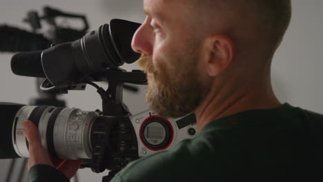 close up of male film camera operator focusing lens on camera shooting movie or video in studio 5