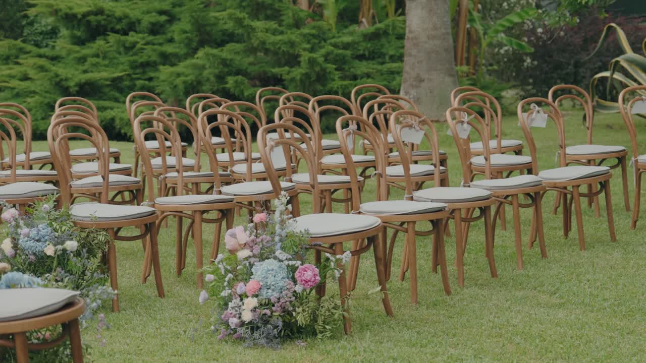 File di sedie di legno disposte per una cerimonia nuziale all'aperto in giardino