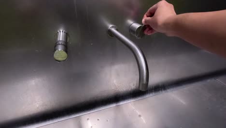 hand turning on a stainless steel faucet