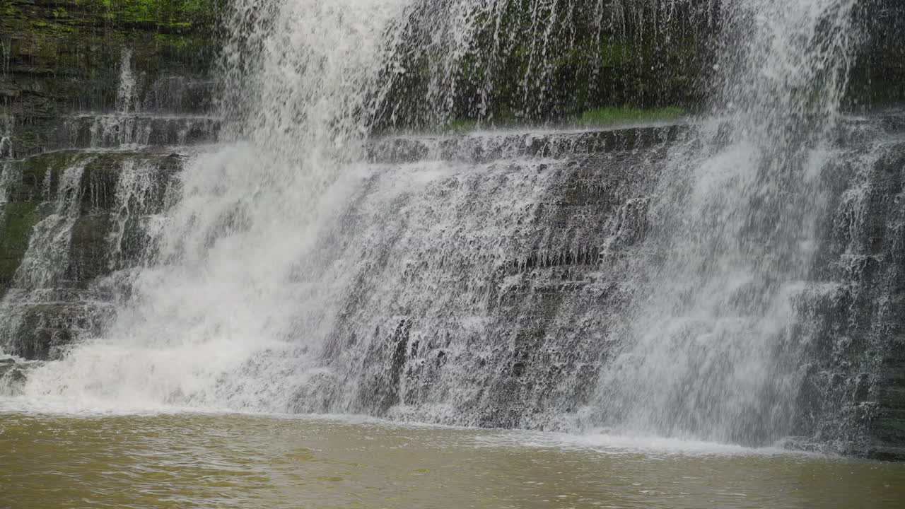 Close-up slow motion of water hitting rocks at Upper Balls Falls showing textures and power