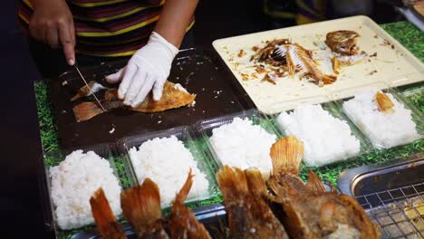 asian person chopping and preparing fish to sell at outdoor market