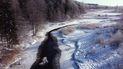 winter partially frozen river in forest landscape aerial view