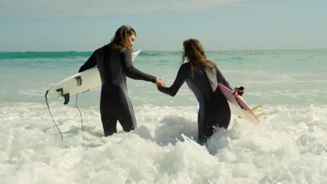 couple with surfboard holding hands on the sea 4k