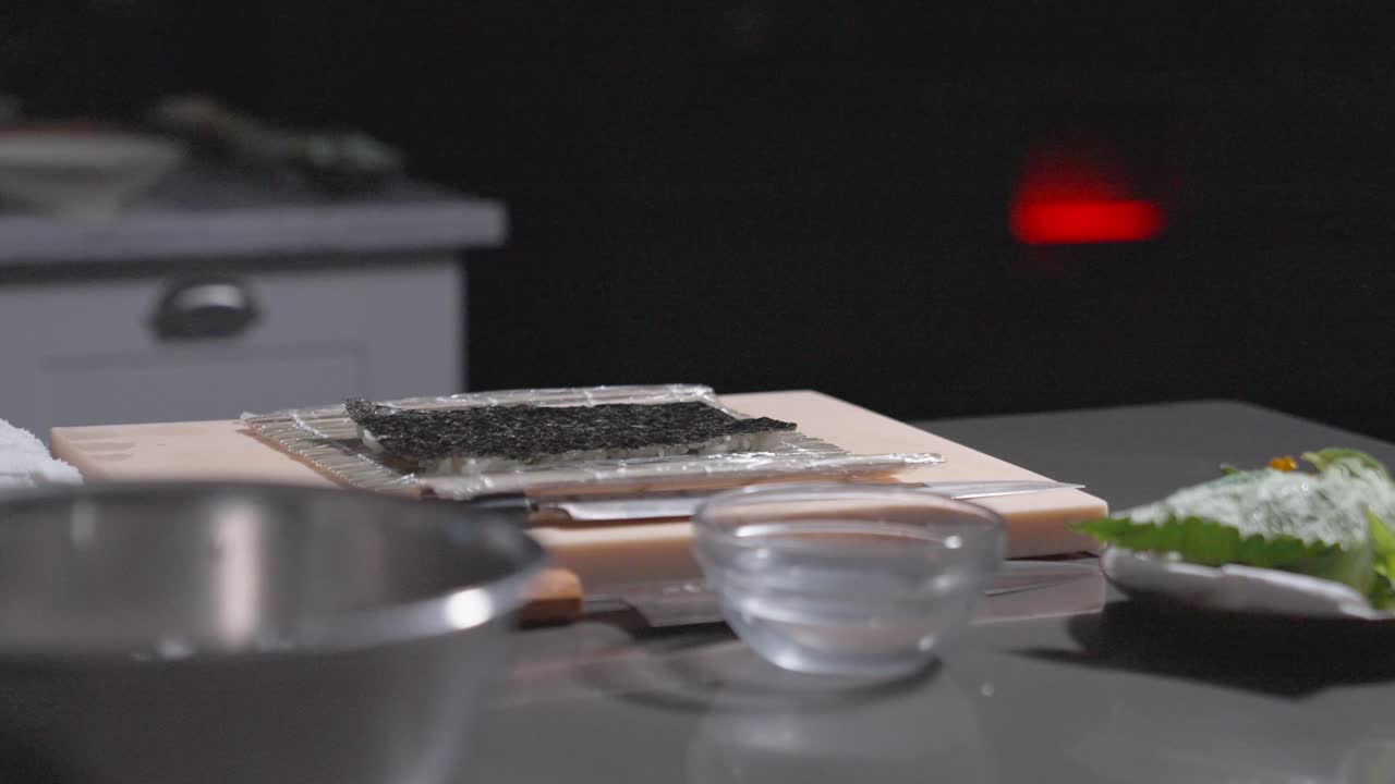 A static shot captures a flat piece of rice and seaweed, ready to be prepared into a sushi roll. Perfect for sushi making, culinary, and food preparation content.