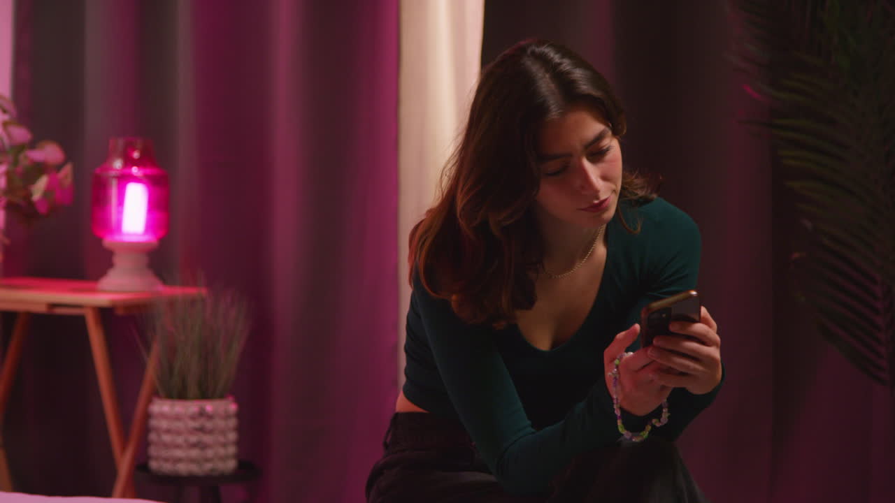 Woman using phone in a cozy, modern bedroom at night.