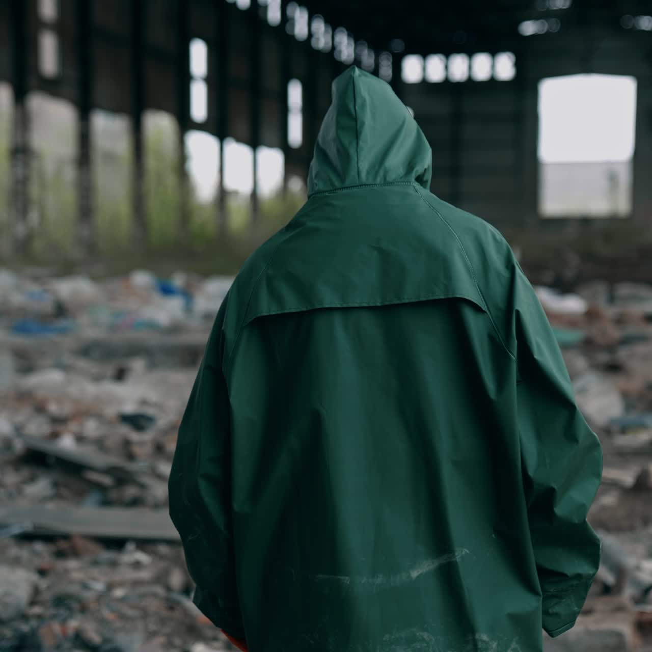 Human in radioactive territory. Person in a hazmat suit and gas mask walking in empty ruined building. Abandoned place after chemical attack. Rear view