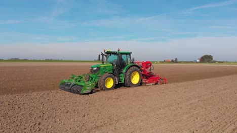 Green-tractor-plowing-brown,-earthy,-dutch-farmland
