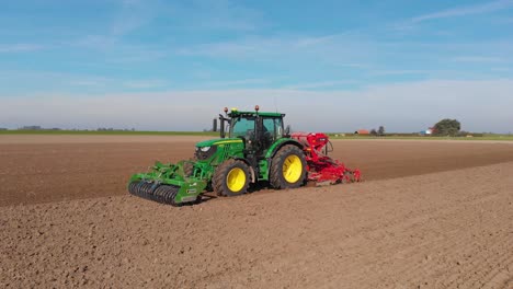 tractor verde arando tierras de cultivo marrones, terrosas y holandesas