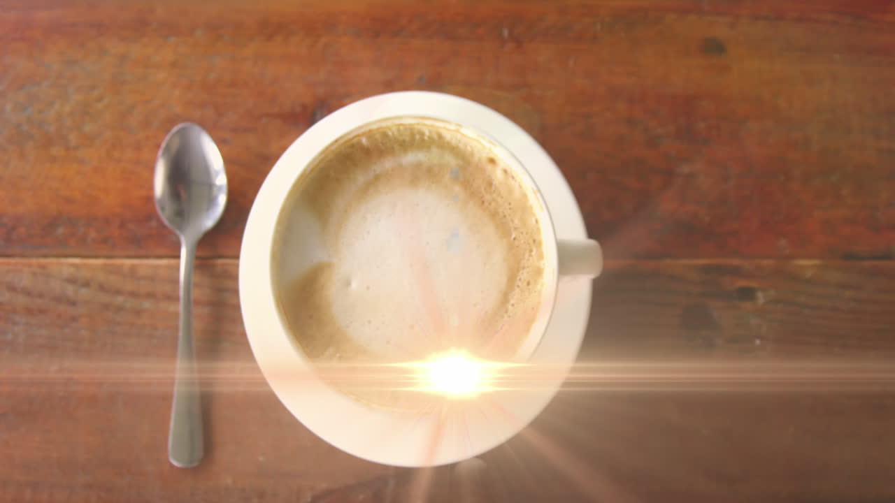 animación del destello de la lente que se mueve por encima de la vista superior de una taza de café con cuchara en una mesa de madera