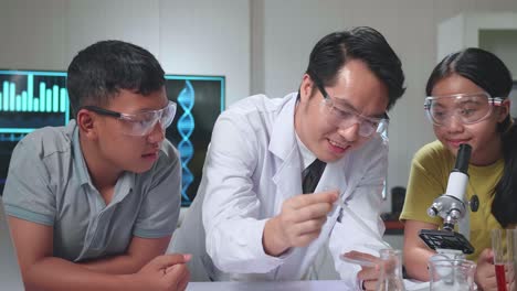 young asian boy and girl learning science experiment in laboratory with teacher in classroom. study with scientific equipment and a microscope