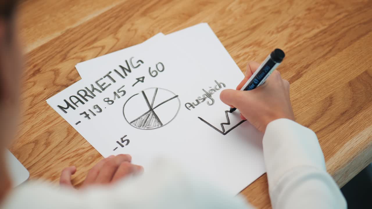 женщина рисует маркетинговую бизнес-модель черной ручкой на листе бумаги за столом в офисе, над плечом