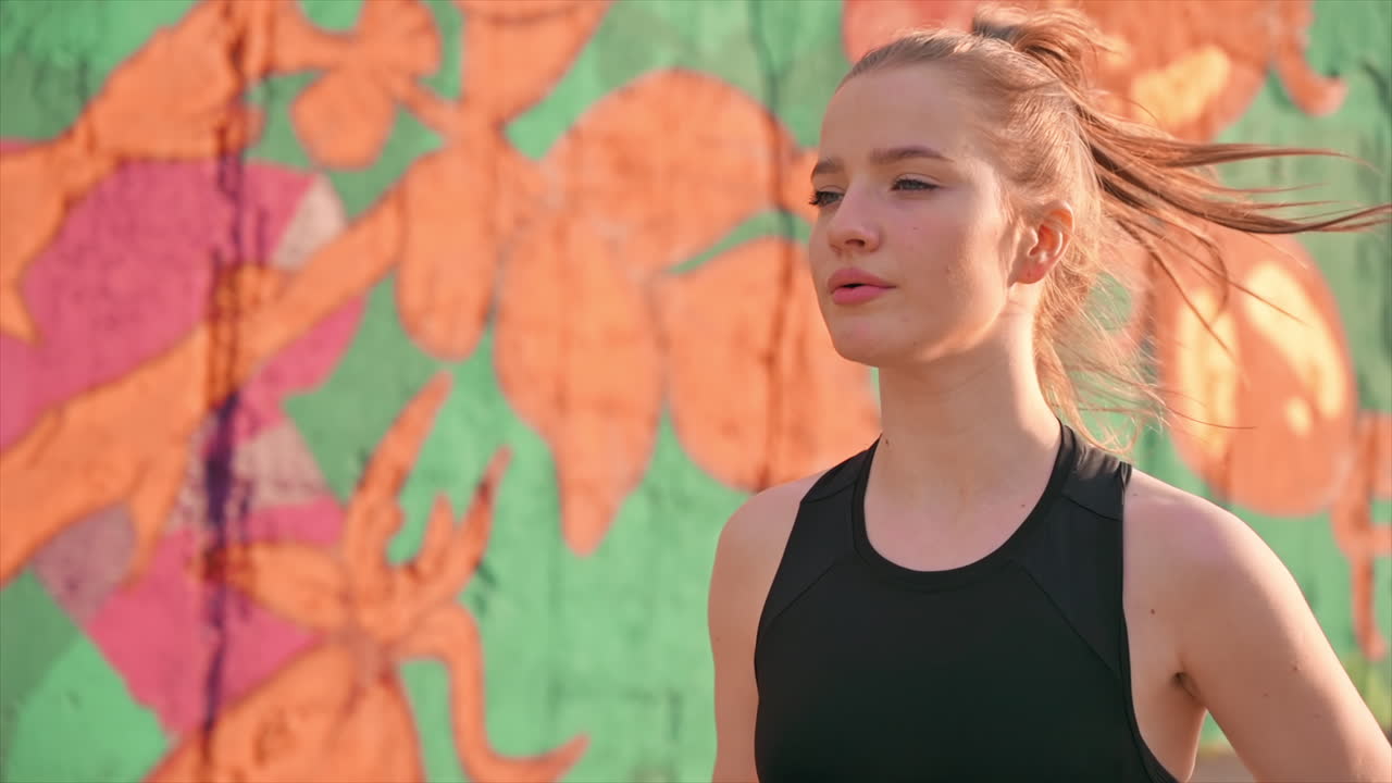 Young blonde woman in sportswear running on the road at outdoors training. Slow motion
