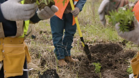 Activistas-Ecologistas-Sostienen-árboles-Pequeños-Para-Plantarlos-En-El-Bosque-Mientras-Su-Compañero-De-Trabajo-árabe-Usa-Un-Rastrillo-Para-Preparar-La-Tierra