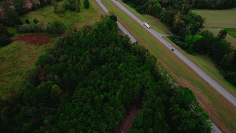 Semi-truck-on-forest-lined-road,-aerial-view-captures-the-essence-of-rural-transport