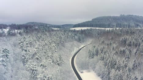 Volar-A-Lo-Largo-De-Un-Camino-Enmarcado-Por-La-Nieve-De-La-Temporada-De-Invierno---Imágenes-De-Drones-En-4k