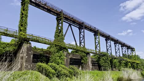 Altes-Historisches-Stahlgerüst,-überwuchert-Von-Der-Natur-Und-überwuchert-Auf-Dem-Industriegelände-Des-Landschaftsparks-Duisbrug-An-Einem-Fluss