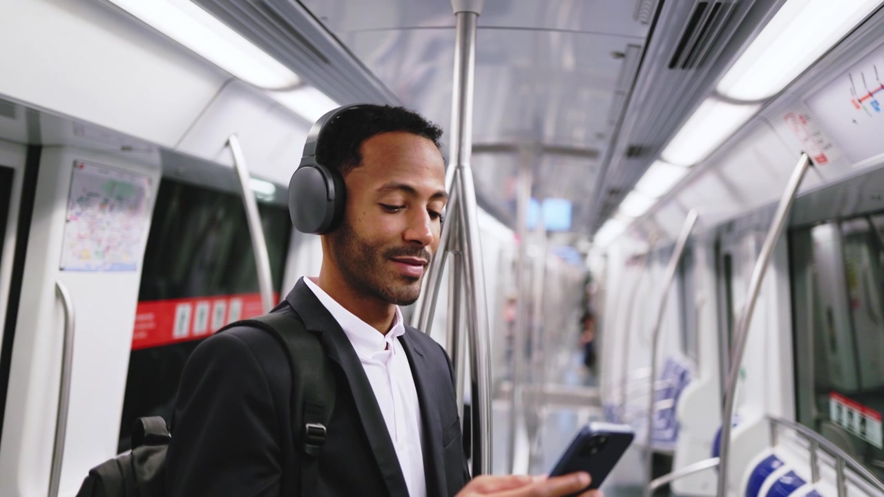 Young Businessman Using Smartphone and Headphones on Subway Train