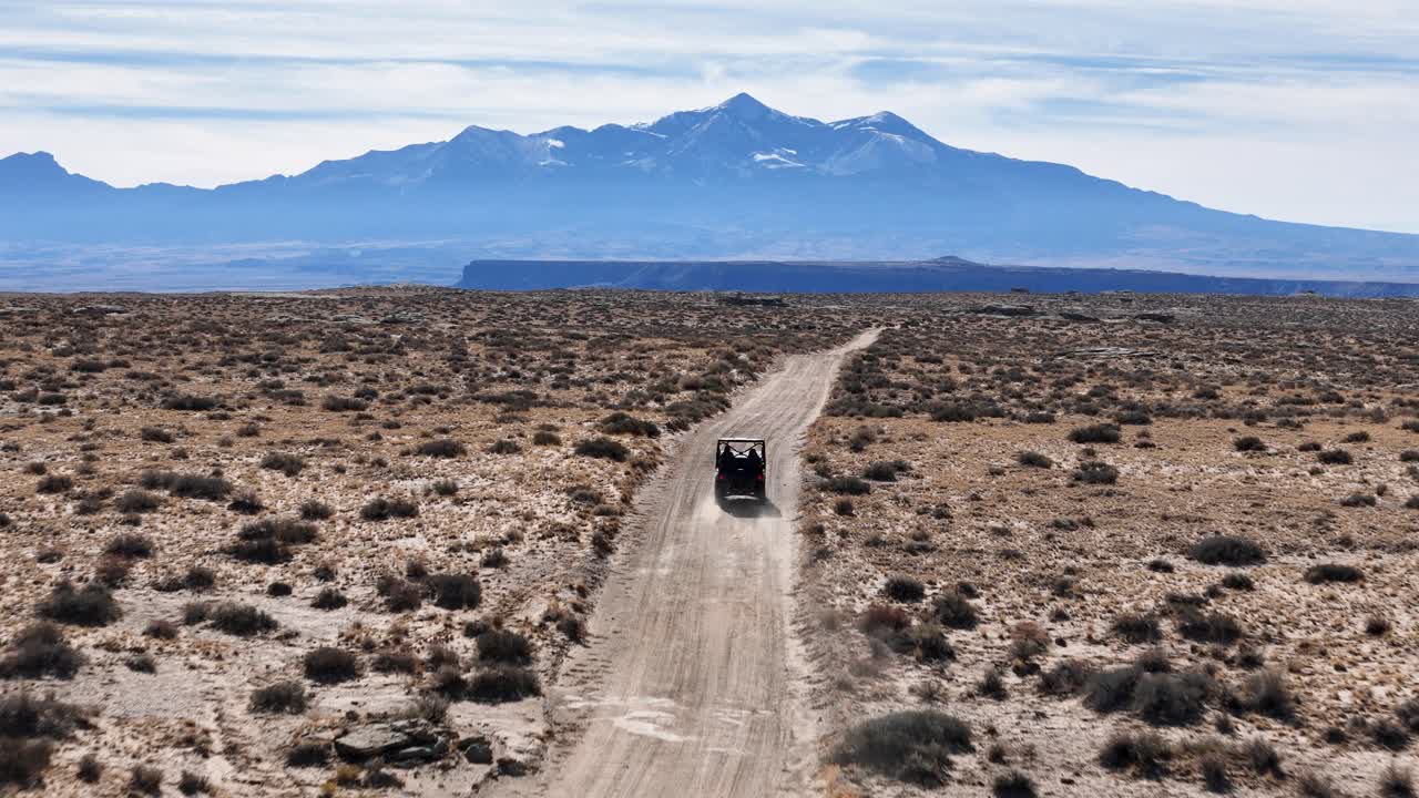 Aerial View of Black Off-Road Vehicle Moving on Dusty Desert Road in Wilderness of Utah USA, Tracking Drone Shot