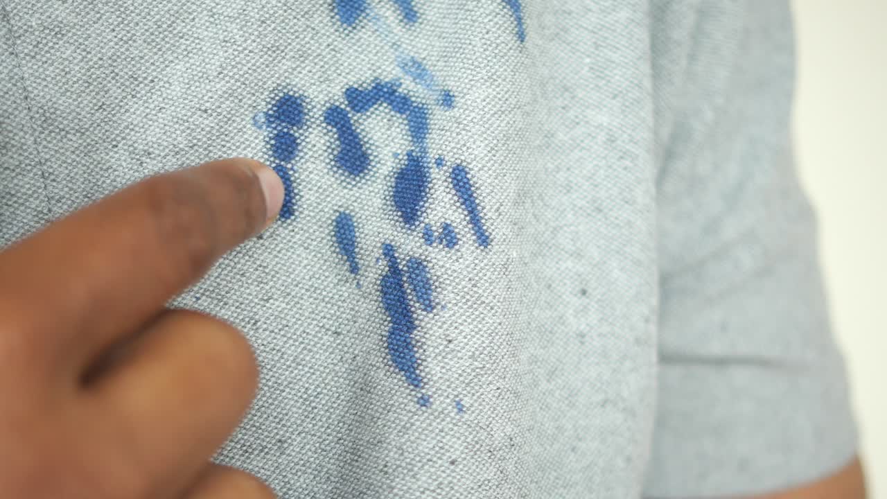 hombre señalando una mancha azul en su camisa