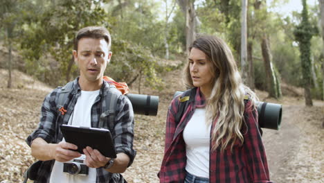 casal de jovens mochileiros andando na floresta