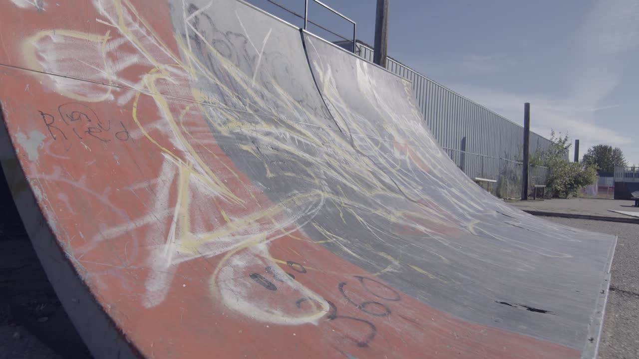 Dolly backwards from skateboard quarter pipe at skate park.