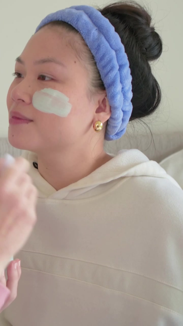 Vertical video: Smiling woman in blue band getting mask on sofa as hand entering jar and brush for c
