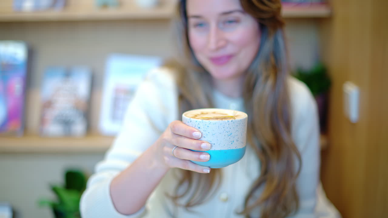 Woman drinking latte art coffee from ceramic cup in a cafe