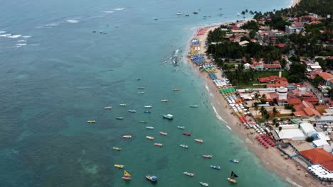 Hochkippen-Der-Luftdrohne-Weitwinkelaufnahme-Des-Hafens-Von-Porto-De-Galinhas-Oder-Hühnerhafen-Mit-Verankerten-Segelbooten-Und-Touristen,-Die-Im-Kristallklaren-Meerwasser-In-Pernambuco,-Brasilien,-Schwimmen