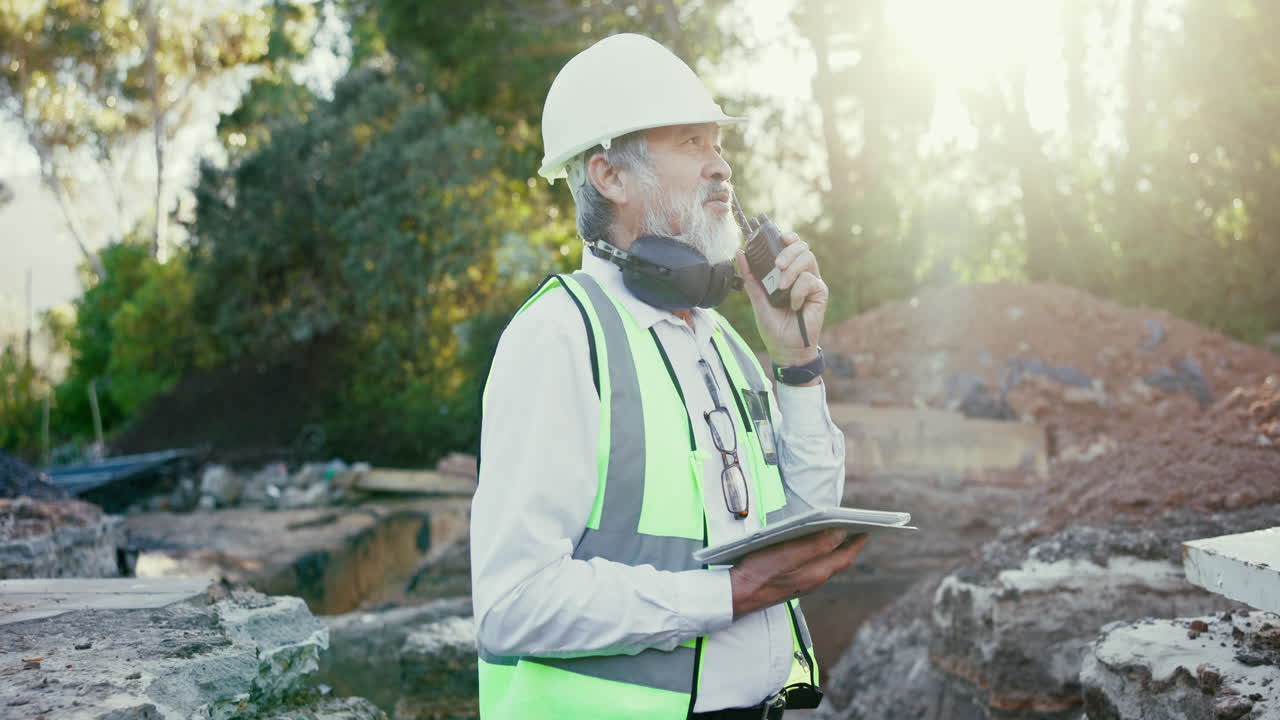 Construction worker on site using walkie talkie and tablet