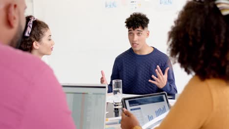 busy diverse business people discussing work at meeting with laptops in office in slow motion