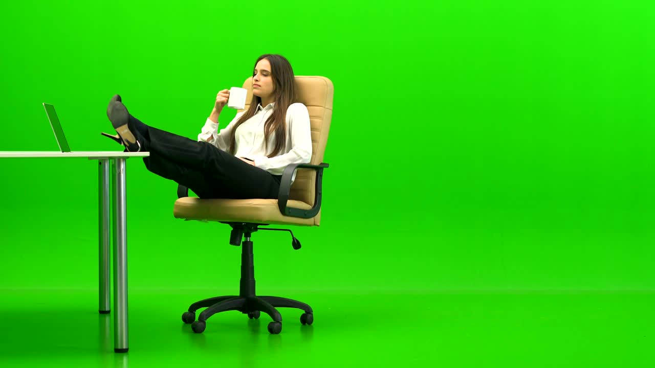 The attractive woman relaxing at the table on the green background