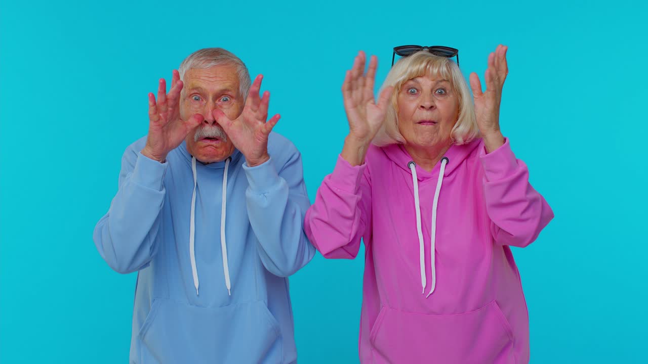 Cheerful senior grandparents pensioners showing tongue making faces at camera, fooling around joking