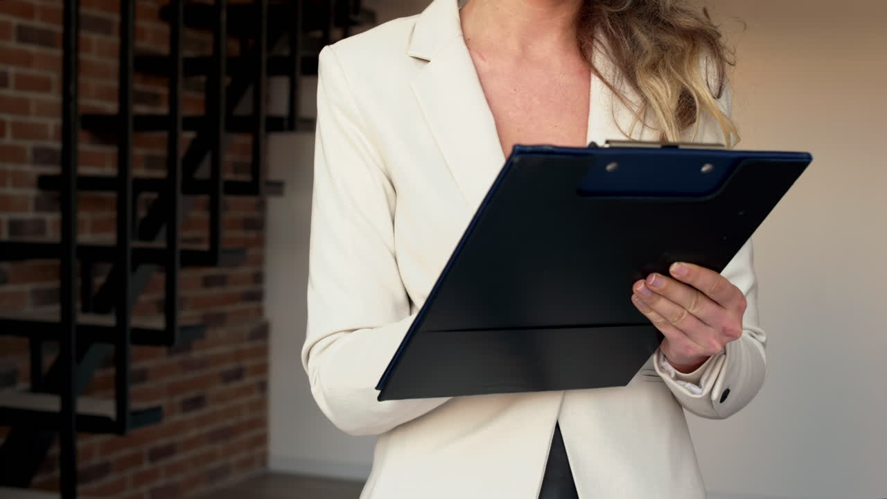 Close up of a professional woman holding a clipboard and pen while preparing for a meeting or presentation in a modern office