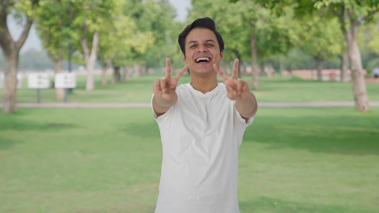 행복한 인디언 남자가 승리의 표시를 보여주고 있습니다.