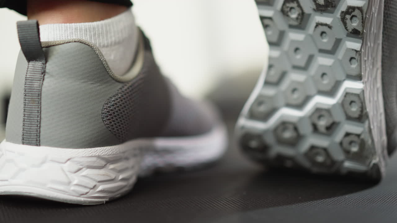 Woman stretches ankle on treadmill closeup. Sportswoman performs leg warming-up before running on training machine. Proper sports preparation
