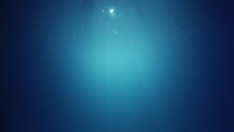 underwater sunlight beams shining from above coming through the deep crystal clear blue water causing a beautiful water lighting reflections curtain