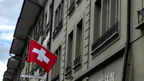 Swiss-Flag-hanging-on-wall-of-house-in-Bern-City-during-sunny-day